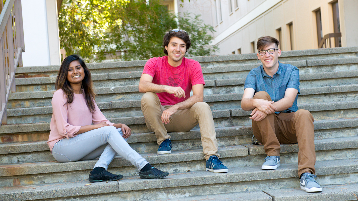 Three graduate students sitting on the steps of the Chemistry Building