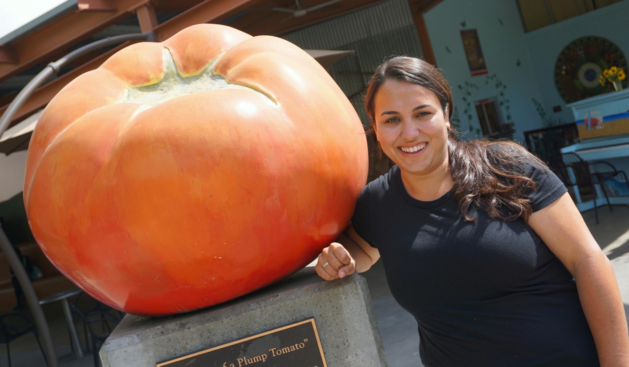 Michele standing next to the tomato art sculpture outside of the Davis Food Co-Op.