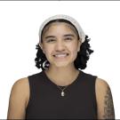 Smiling young woman headshot with headband, necklace, black sleeveless top, arm tattoo